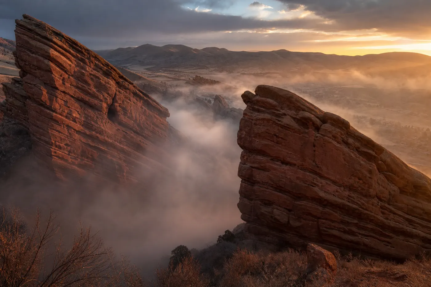 Ancient red sandstone formations at Red Rocks Park at dawn with morning mist swirling between the monoliths