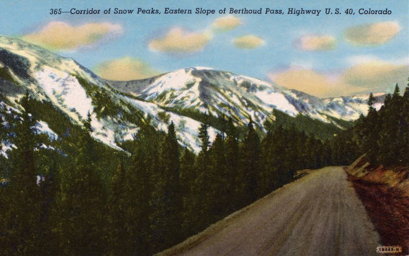 Hand-tinted 1941 postcard of a gravel-shouldered US-40 climbing through pine forest toward snow-covered peaks on the eastern slope of Berthoud Pass