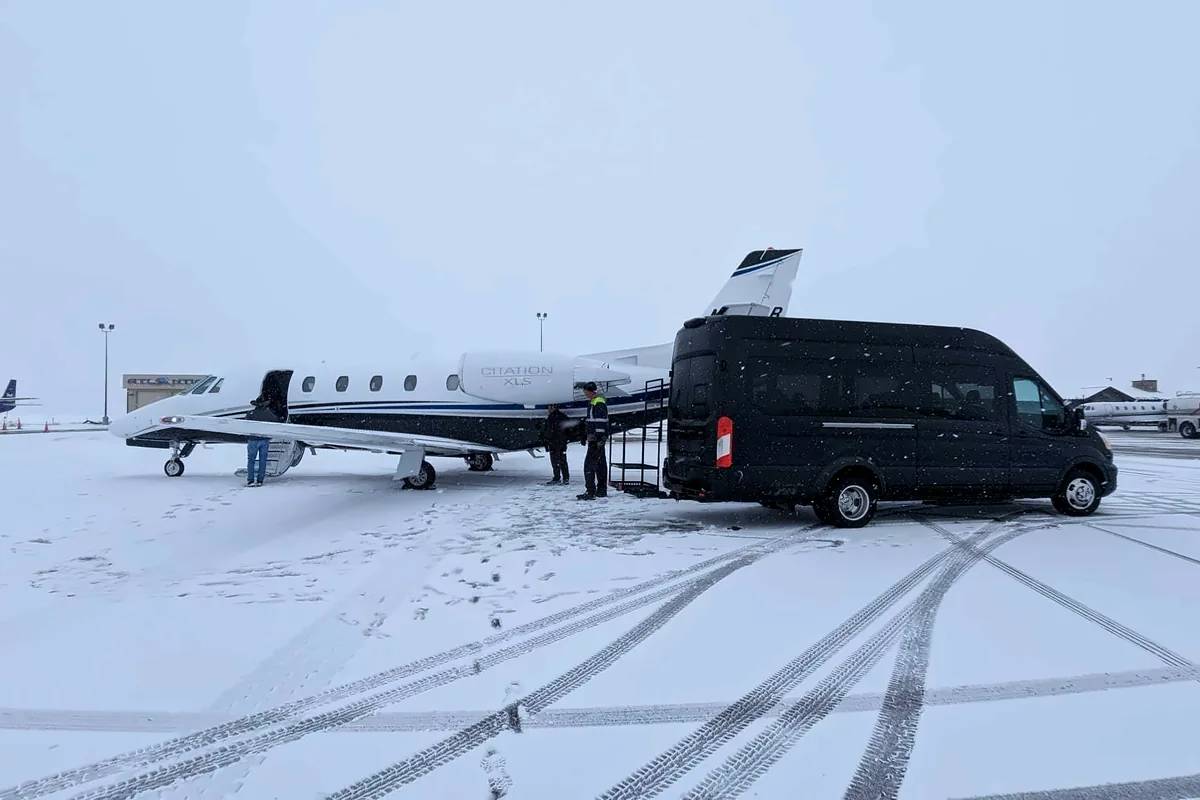 Black passenger van at the airstair of a Cessna Citation XLS on the snowy FBO ramp at Yampa Valley Regional Airport in Hayden