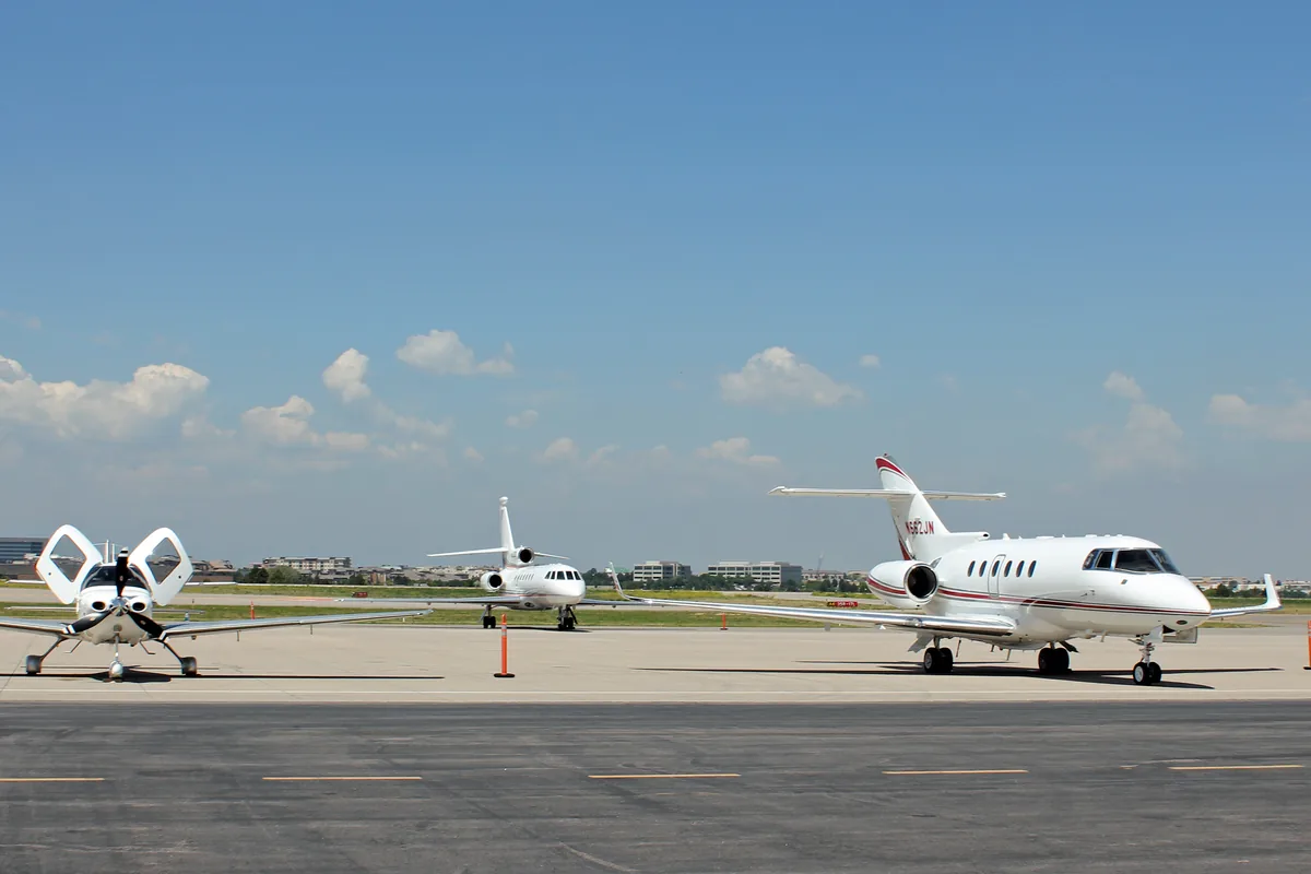 Business jets parked on the apron at a Colorado airport with mountains behind