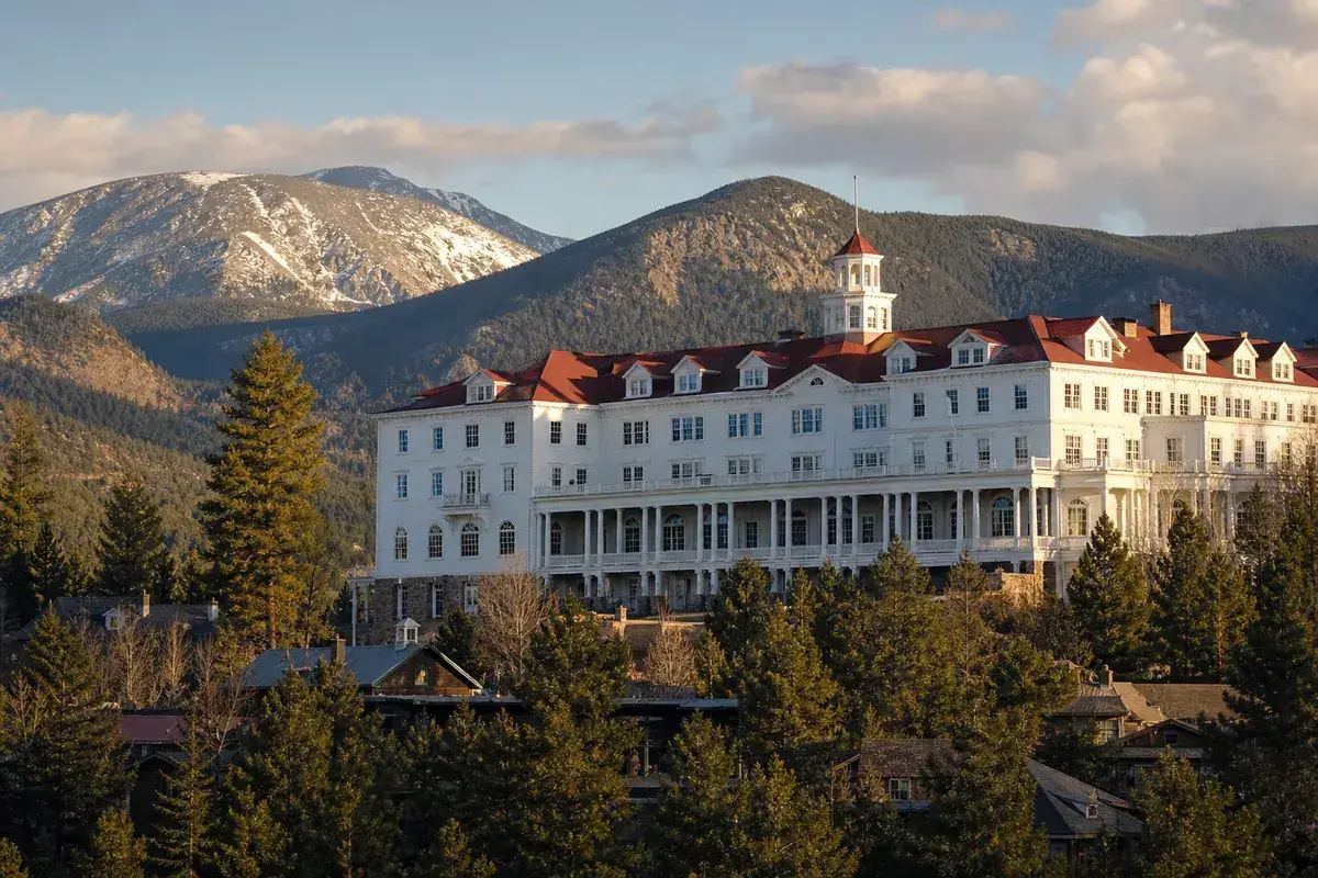 Historic white mountain resort hotel with red roof above Estes Park, Colorado, at golden hour