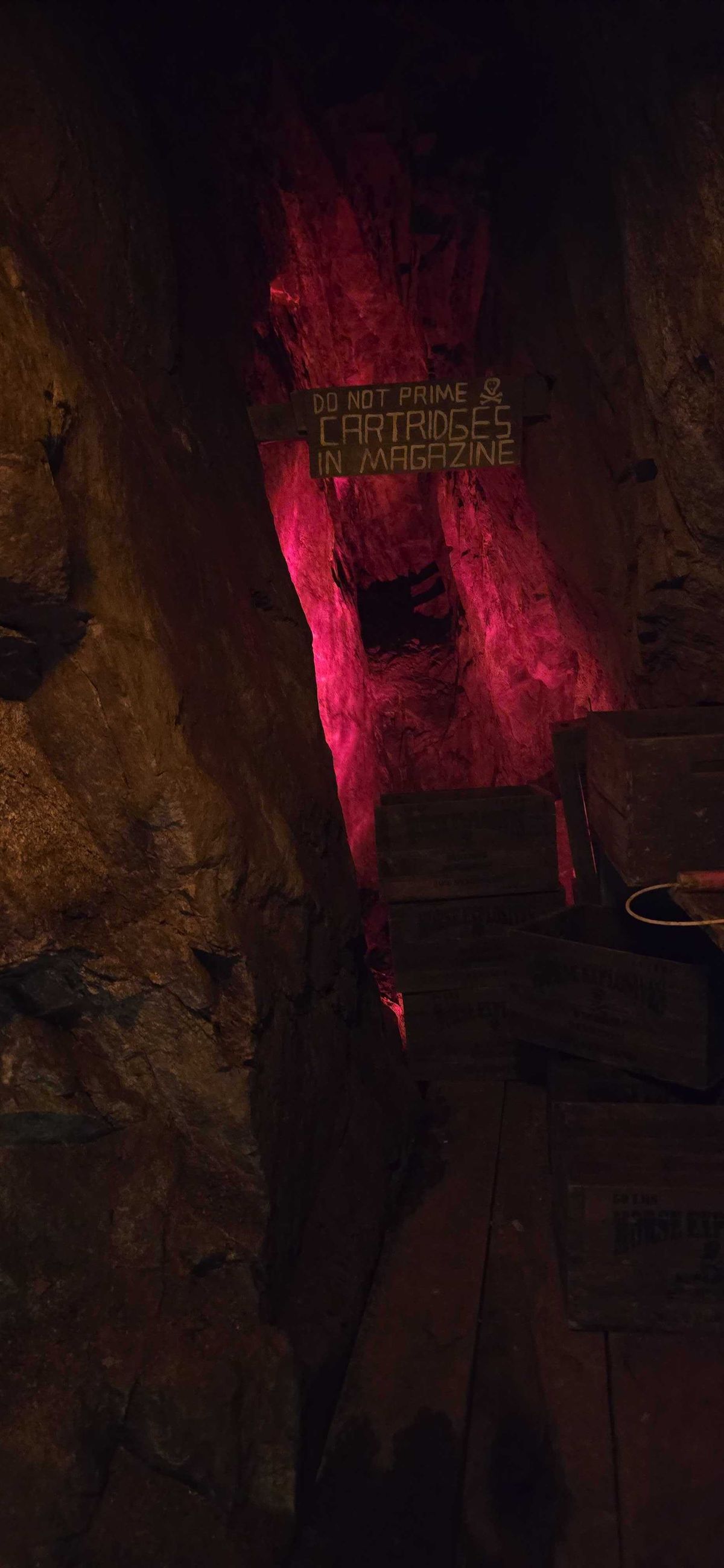 Original warning sign — Do Not Prime Cartridges in Magazine — with skull and crossbones, lit in red inside the Lebanon Mine