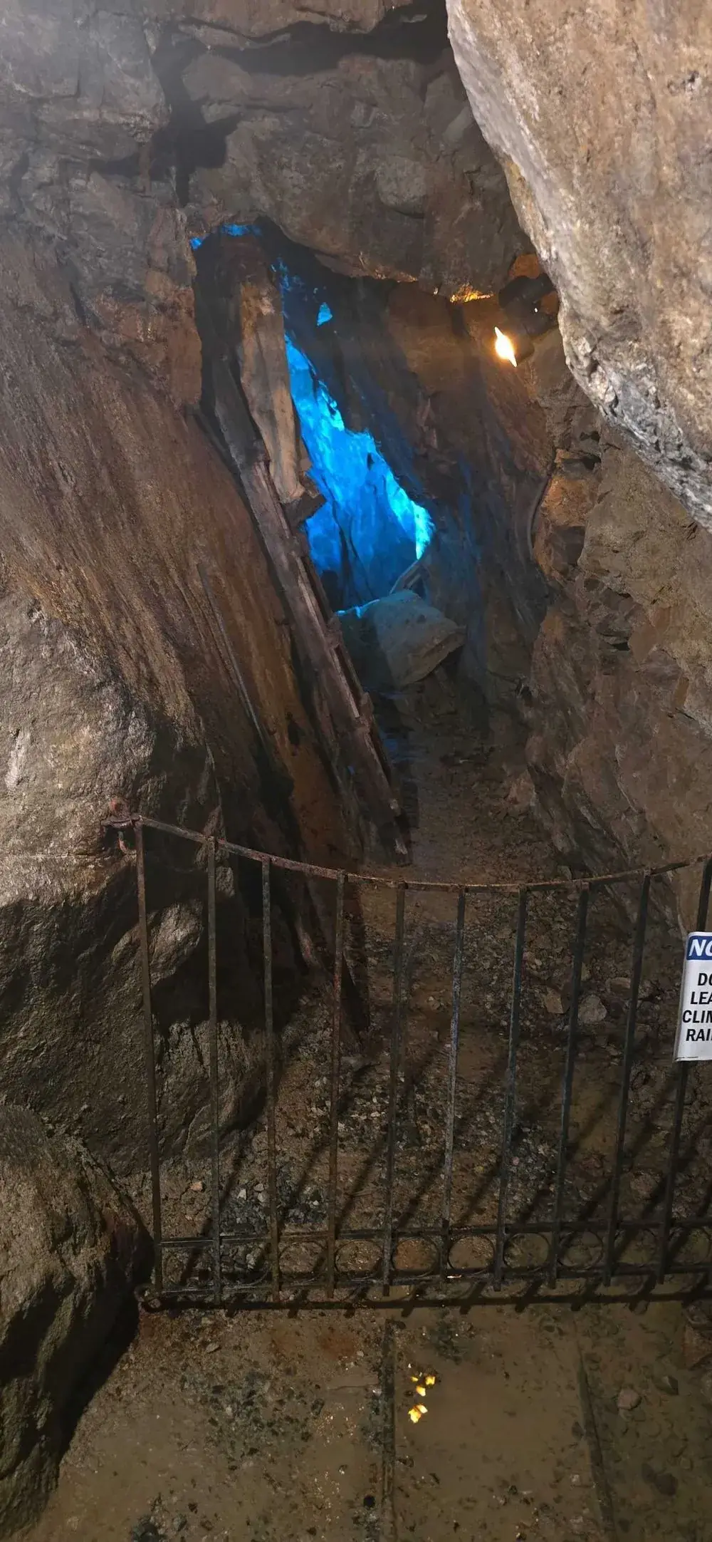 Blue-lit mine shaft with old timber supports, water seepage and mineral deposits