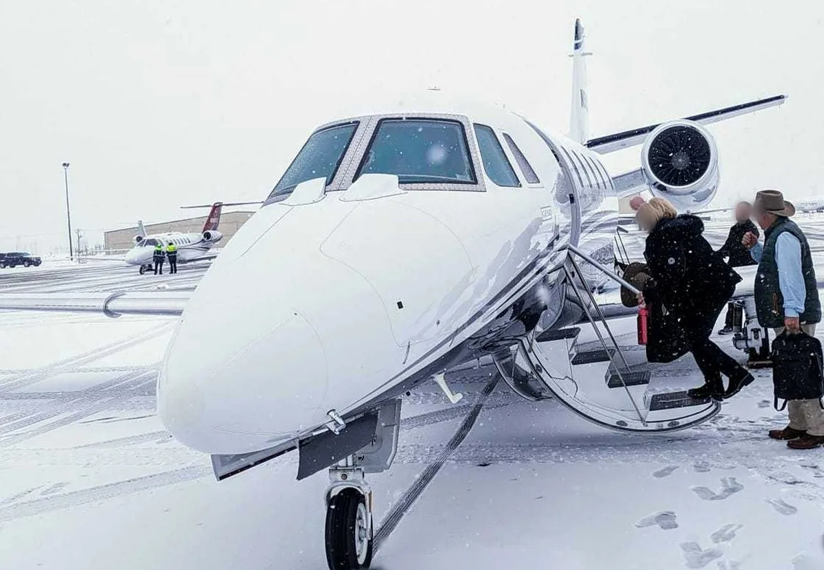 Passengers boarding a Cessna Citation XLS by the airstair in falling snow at Atlantic Aviation, Hayden