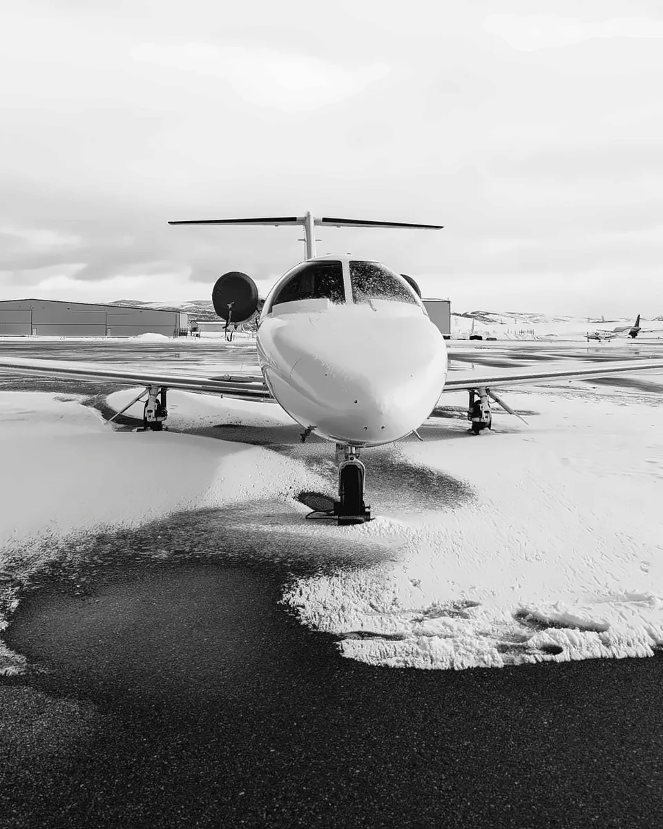 Light business jet parked nose-on on the snow-covered Atlantic Aviation ramp in Hayden, black and white