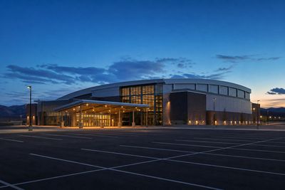 Exterior of a mid-size Colorado arena at blue hour with empty parking lot in the foreground