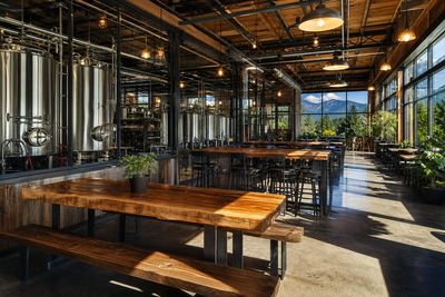 Craft brewery taproom with stainless fermentation tanks and long wooden tables, Colorado