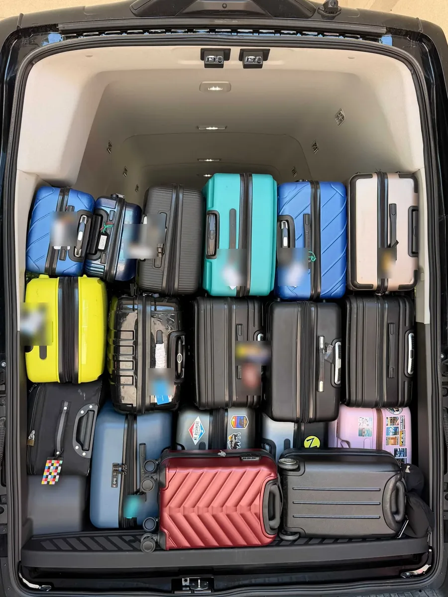 Luggage loaded in the rear of an Arion luxury van: 14 checked bags stacked floor to ceiling