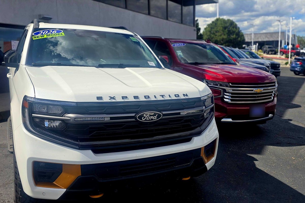 A Colorado dealership lot on a Sunday afternoon, closed by law, with new and used SUVs parked and no one on the lot